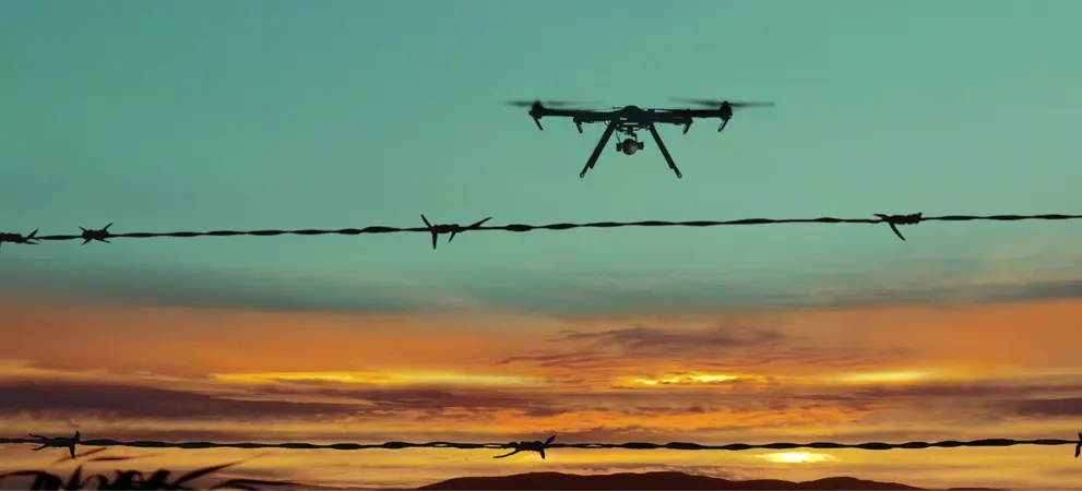 drone flying over a security fence